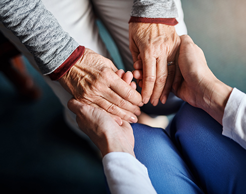 Nurse caretaker holding the hands of an elderly patient at a healthcare staffing agency